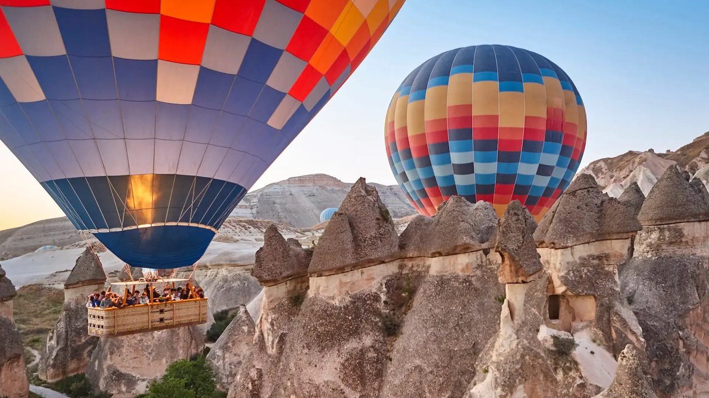 Kapadokya'da gün doğumunda peribacaları ve sıcak hava balonları